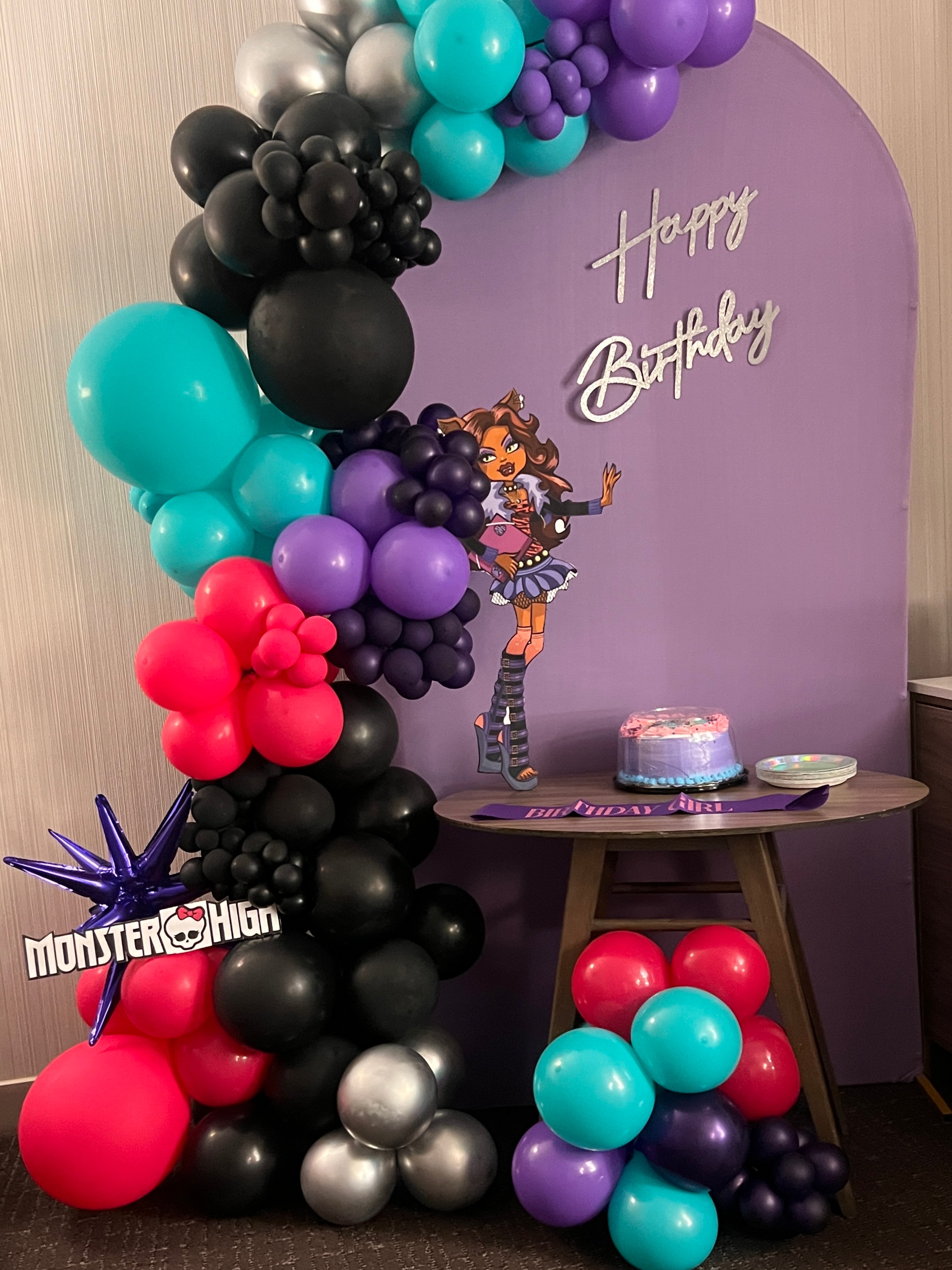 Monster High themed birthday setup with teal and black balloon arch