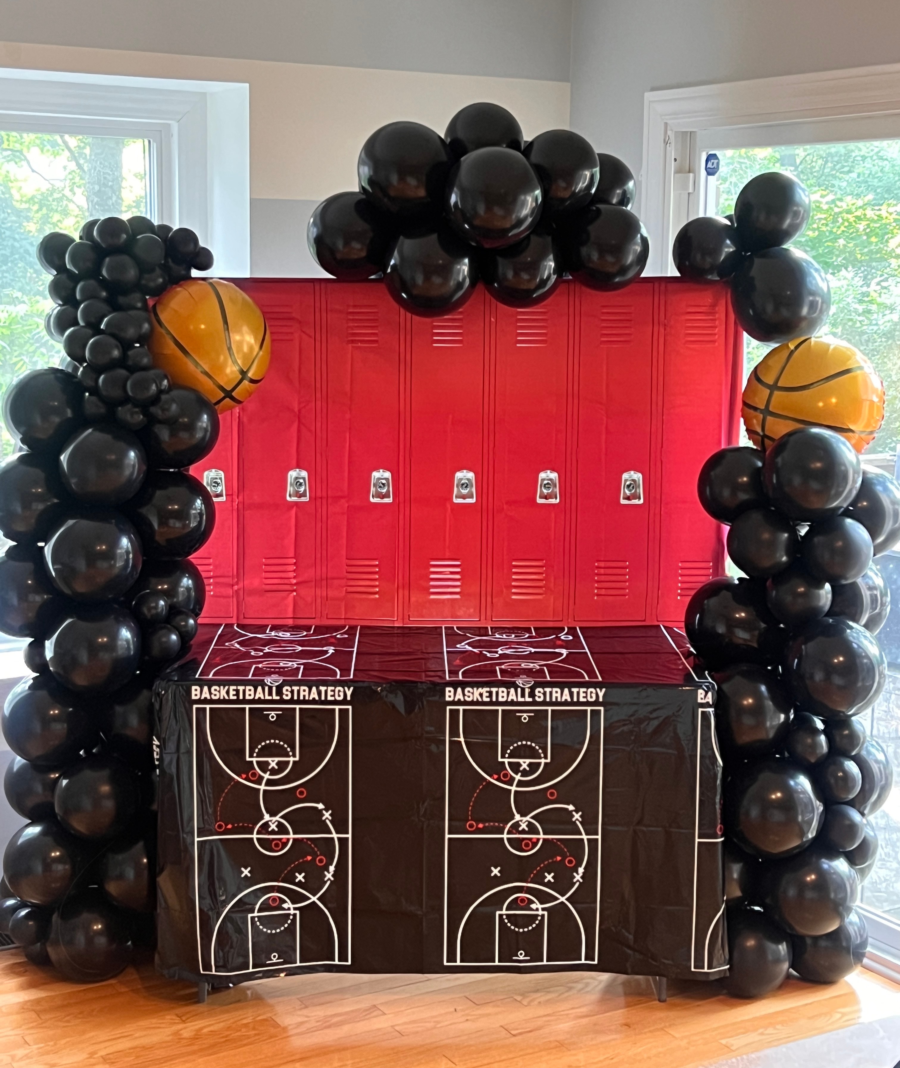 Basketball themed party setup with black balloon arch and red lockers