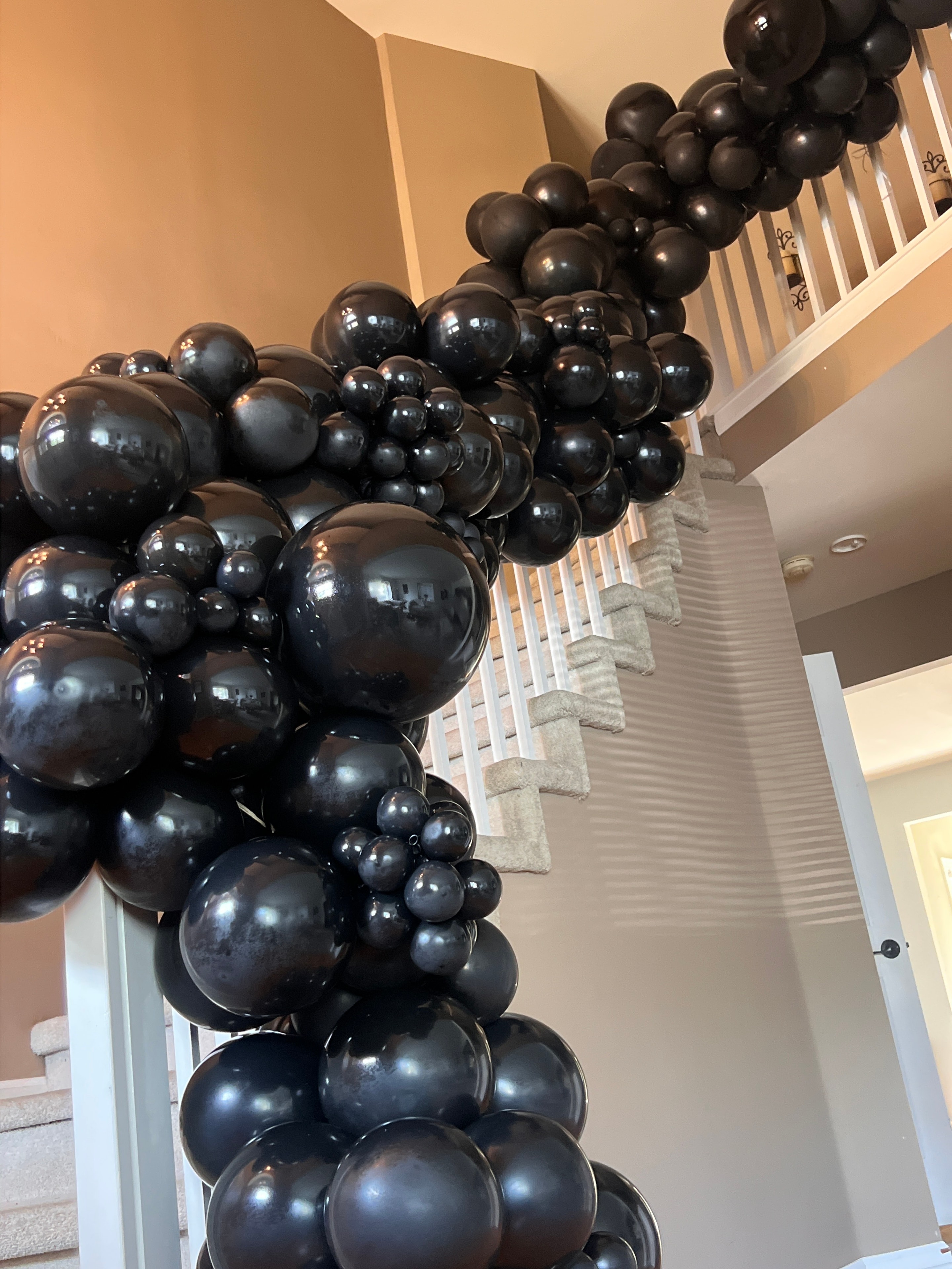 Black balloon garland draped over staircase